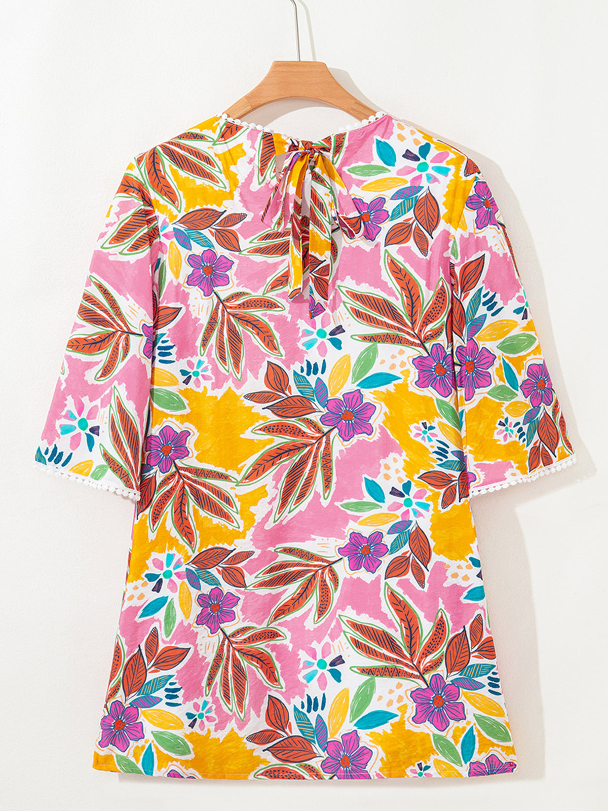 Back view of the floral mini dress on a hanger showing the tie neckline