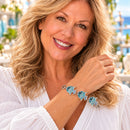 Styling photo of a woman in a white blouse wearing a bracelet with turquoise and blue snap charms