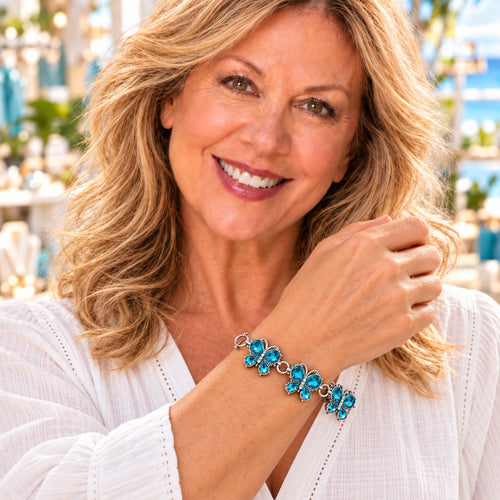 Styling photo of a woman in a white blouse wearing a bracelet with blue snap charms