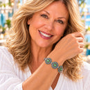 Styling photo of a woman in a white blouse wearing a bracelet with green and blue snap charms