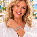 Styling photo of a woman in a white blouse wearing a bracelet with silver and clear snap charms
