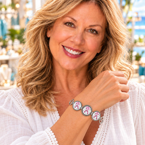 Styling photo of a woman in a white blouse wearing a bracelet with pink and silver snap charms