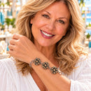 Styling photo of a woman in a white blouse wearing a bracelet with brown and gold snap charms