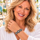 Styling photo of a woman in a white blouse wearing a bracelet with black and silver snap charms