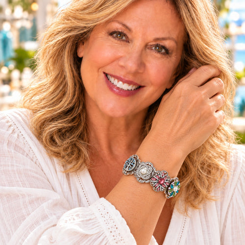 Woman wearing a silver-tone stretch bracelet with colored snap charms