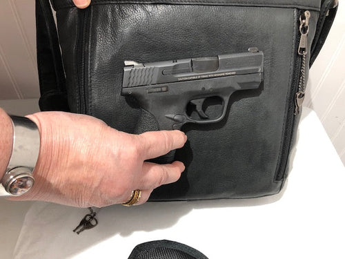 Hand showing a demonstration handgun inside the black Janko Ruth handbag compartment