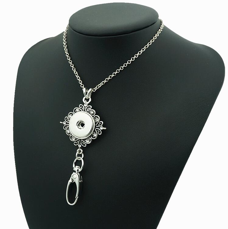 Silver-tone Sandy Snap lanyard necklace with a floral snap setting and badge clip on a black display bust